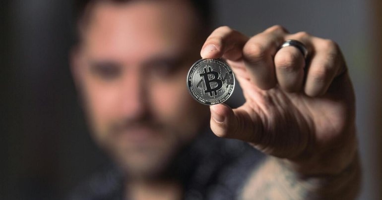 Imagen principal del artículo: una persona sosteniendo una moneda bitcoin en su mano.
