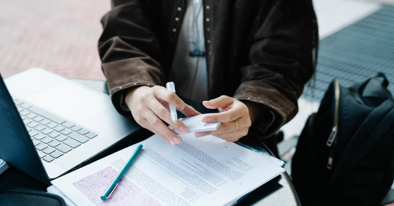 Una persona revisando sus apuntes mientras toma clase en línea.