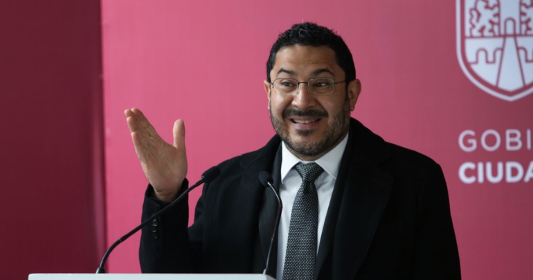Martí Batres dando un discurso frente a un atril con micrófono.