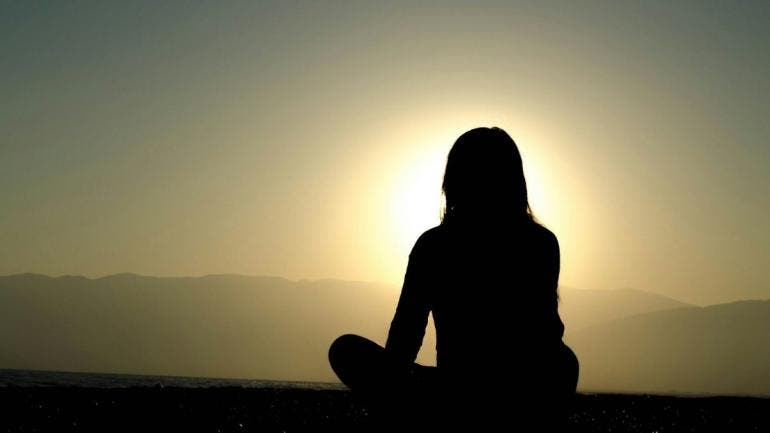 Persona de espaldas contemplando la puesta de sol, simbolizando resiliencia, justicia climática y sostenibilidad en el Caribe, con Marian Vidaurri.