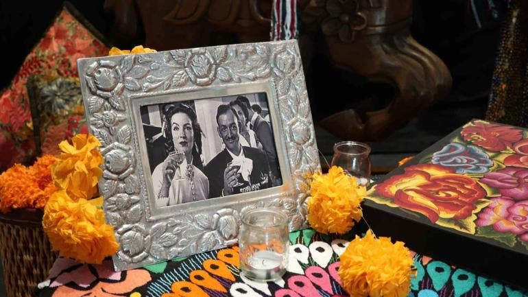 Altar del Día de los Muertos en la Embajada de México en Rabat con fotos, velas, pan, flores de cempasúchil y objetos que recuerdan a María Félix y Jorge Negrete.