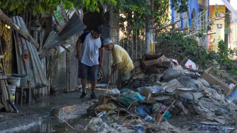 Dos hombres apilan escombros en la calle en el municipio de Álamo