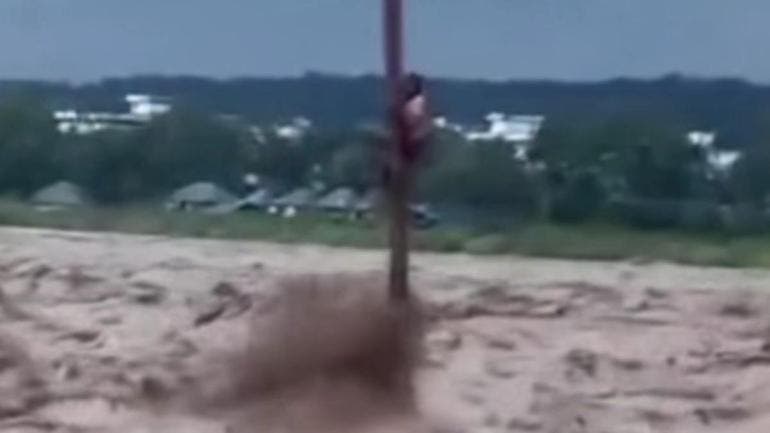 Joven aferrado a un poste tras lluvias