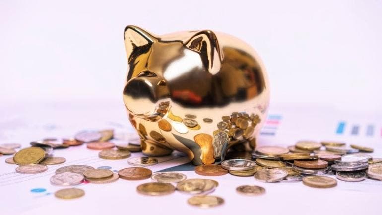 Alcancía en forma de cerdito rodeada de dinero, simbolizando ahorro y buena administración del dinero para el retiro.