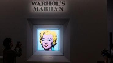Personas observan el retrato "Shot Sage Blue Marilyn" de Andy Warhol durante una conferencia de prensa en Christie's, en Nueva York.