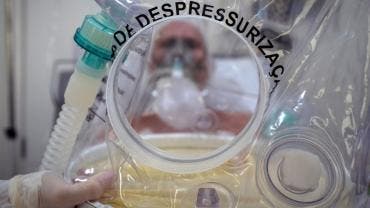 Un trabajador de la salud muestra un casco burbuja, utilizado en pacientes con la covid-19 en Sao Leopoldo, Brasil.