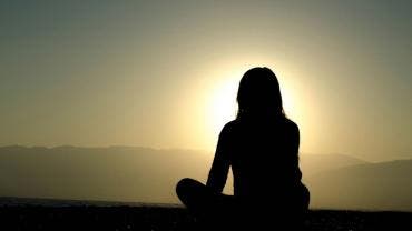 Persona de espaldas contemplando la puesta de sol, simbolizando resiliencia, justicia climática y sostenibilidad en el Caribe, con Marian Vidaurri.