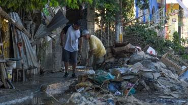 Dos hombres apilan escombros en la calle en el municipio de Álamo 