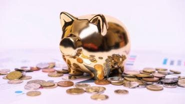 Alcancía en forma de cerdito rodeada de dinero, simbolizando ahorro y buena administración del dinero para el retiro.