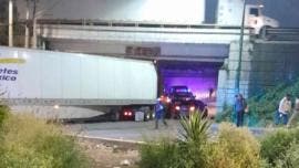 Tráiler queda atorado en bajo puente de Perinorte
