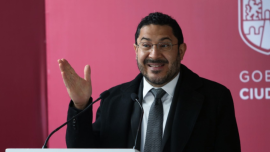 Martí Batres dando un discurso frente a un atril con micrófono.