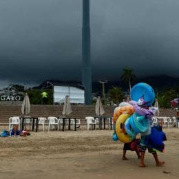 Vendedores caminan en una playa de Acapulco