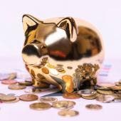 Alcancía en forma de cerdito rodeada de dinero, simbolizando ahorro y buena administración del dinero para el retiro.