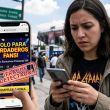 Joven mexicana revisa anuncio de fraude de boletos de concierto en smartphone en CDMX.