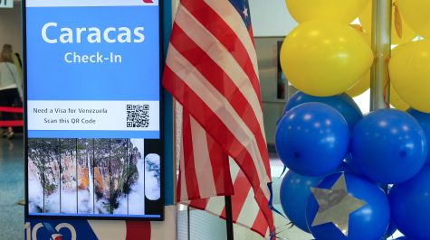 Fotografía que muestra globos con los colores de la bandera venezolana junto a una panel anunciando el vuelo con destino a Caracas, en el aeropuerto Internacional de Miami en Florida. (EFE)
