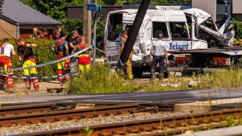 La furgoneta de transporte escolar accidentada es remolcada en el lugar de una colisión con un tren en un cruce ferroviario en Buggenhout, Bélgica. (EFE)
