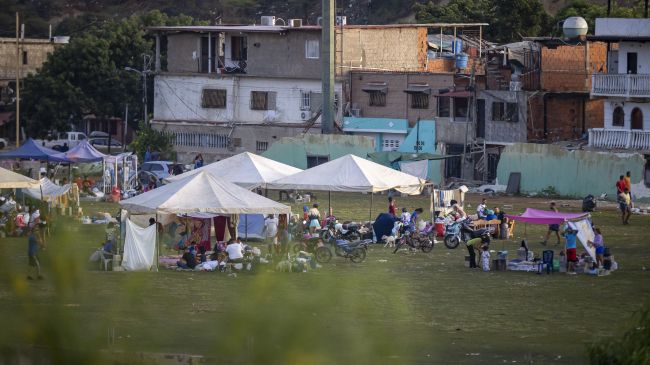 Recostados en colchones, sábanas, sillas, carpas y campamentos improvisados, cientos de personas duermen en el asfalto, jardineras, plazas y canchas en Catia La Mar, una de las ciudades más afectadas por los terremotos de magnitud 7,2 y 7,5 ocurridos el miércoles en Venezuela. (EFE)