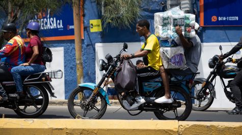 Personas transportan paquetes este viernes, durante un saqueo a un establecimiento comercial, en Catia La Mar, Venezuela. (EFE).