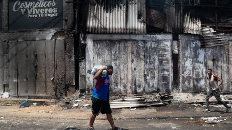 Una persona carga un paquete este viernes, durante un saqueo a un establecimiento comercial, en Catia La Mar, Venezuela. (EFE).