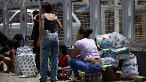Personas esperan con paquetes en una calle este viernes, durante un saqueo a un establecimiento comercial, en Catia La Mar, Venezuela. (EFE).