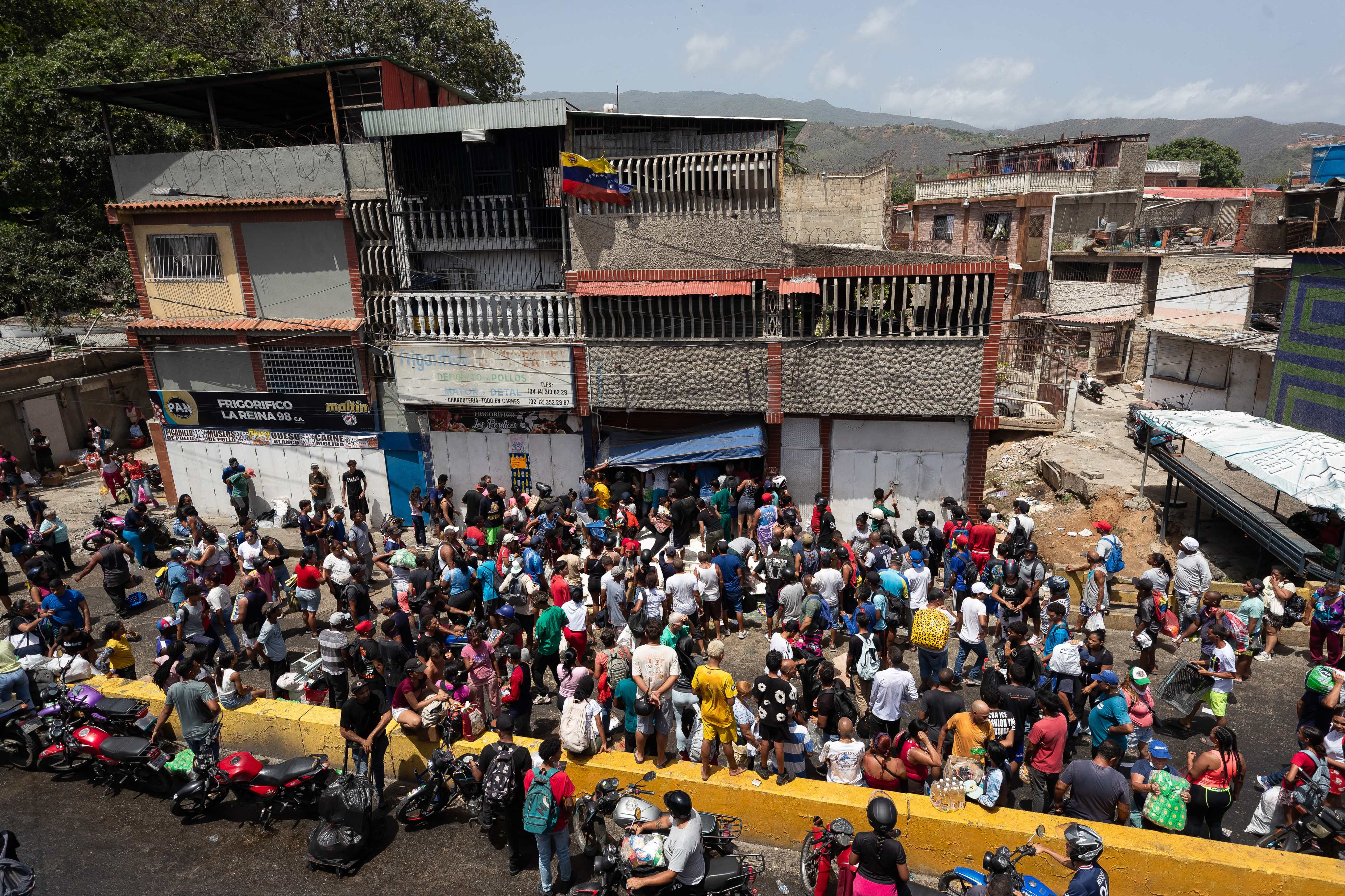 Personas observan el saqueo a un establecimiento comercial este viernes, en Catia La Mar, Venezuela. (EFE).