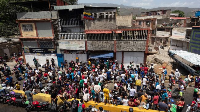 Personas observan el saqueo a un establecimiento comercial este viernes, en Catia La Mar, Venezuela. (EFE).
