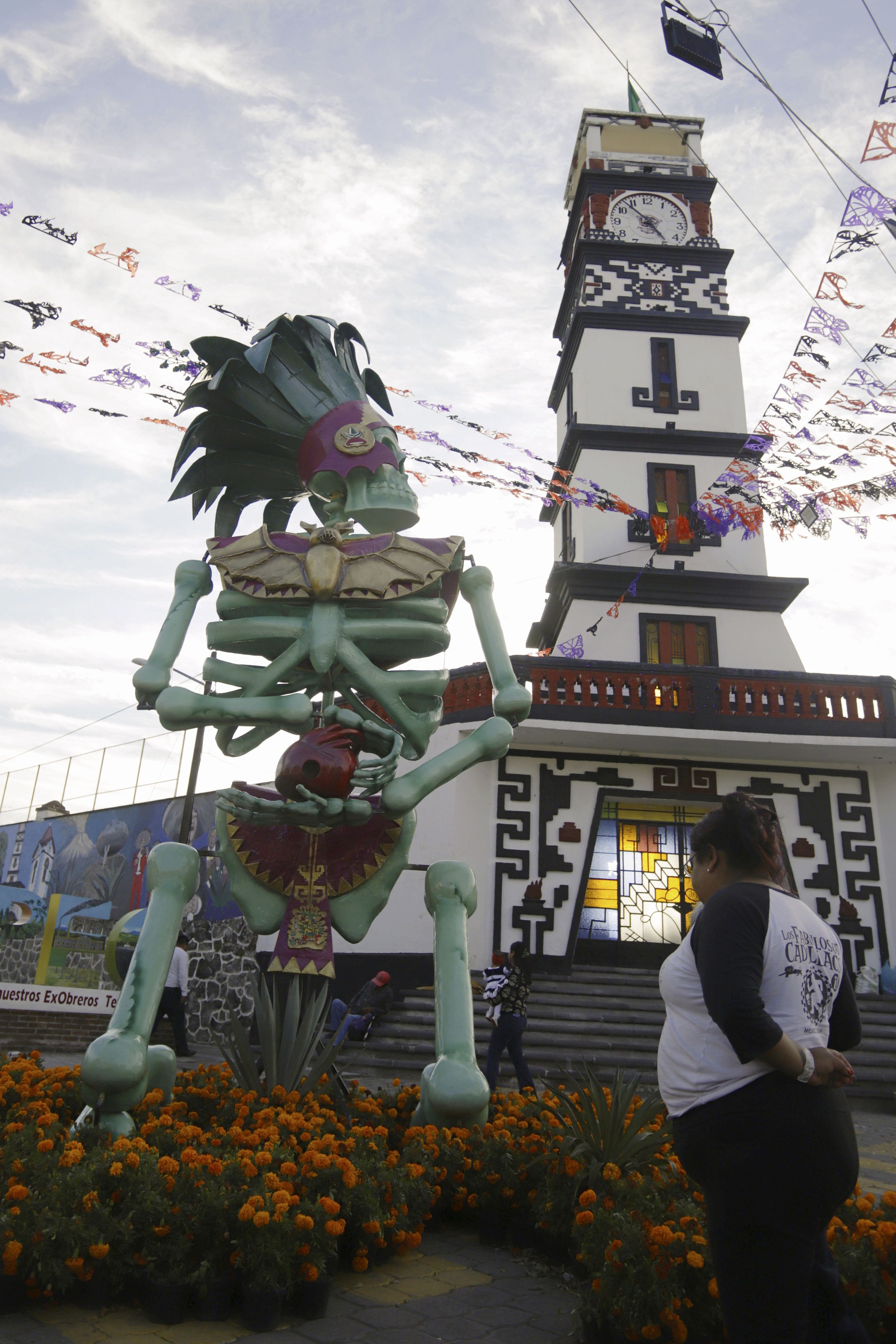Una persona observa una catrina monumental entre los atractivos del Día de Muertos en Atlixco, Puebla (México). Las figuras, inspiradas en dioses prehispánicos, adornan campos de cempasúchil, plazas y calles del municipio. EFE/ Hilda Ríos