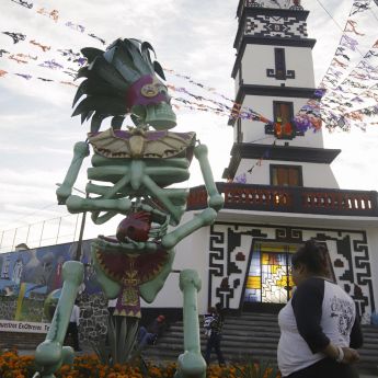 Una persona observa una catrina monumental entre los atractivos del Día de Muertos en Atlixco, Puebla (México). Las figuras, inspiradas en dioses prehispánicos, adornan campos de cempasúchil, plazas y calles del municipio. EFE/ Hilda Ríos
