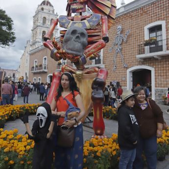Personas posan junto a una catrina monumental durante las celebraciones del Día de Muertos en Atlixco, Puebla (México), donde estas figuras inspiradas en dioses prehispánicos adornan espacios públicos. EFE/ Hilda Ríos